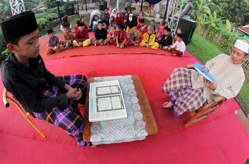Juri (kanan) menyimak peserta lomba membaca Alquran di Kampung Beberan, Serang, Banten, Selasa (21/5). /Antara Foto. 