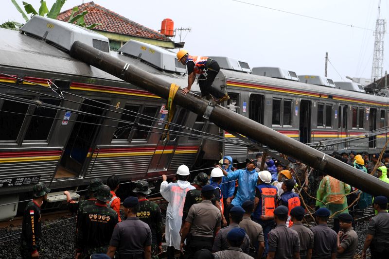 Petugas berusaha memindahkan tiang listrik yang menimpa gerbong KRL Commuter Line 1722 yang anjlok di pintu perlintasan Kebon Pedes, Tanah Sareal, Kota Bogor, Jawa Barat, Minggu (10/3). (Antara Foto).