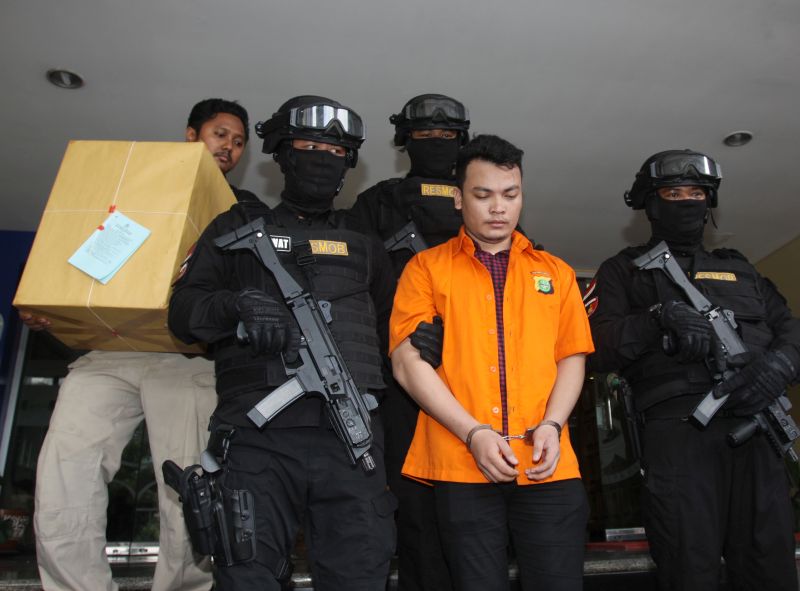 Polisi menjaga tersangka kasus pembunuhan satu keluarga di Bekasi, Haris Simamora atau HS (kedua kanan) dihadirkan dalam Pelimpahan berkas perkara pembunuhan di Polda Metro Jaya, Jakarta, Kamis (21/2). (Antara Foto).