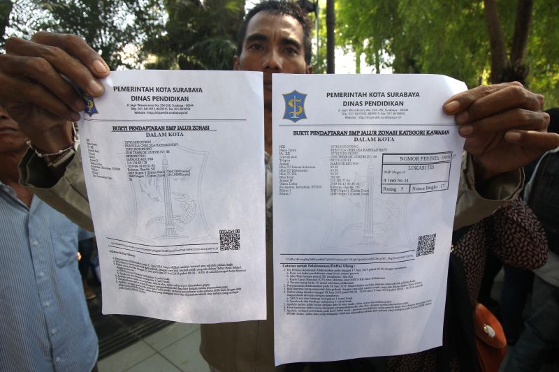Warga menunjukkan bukti pendaftaran SMP jalur zonasi saat berunjukrasa di Balai Kota Surabaya, Jawa Timur, Rabu (19/6). /Antara Foto. 