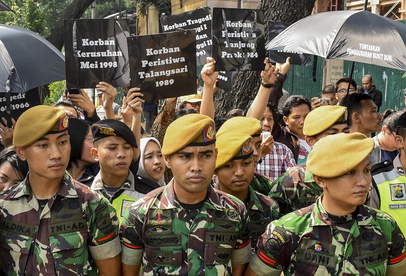 Pegiat HAM melakukan aksi memperingati Hari HAM Internasional 2018 dengan pengawalan personel TNI dan Polri di depan kantor Komnas HAM./ Antara Foto