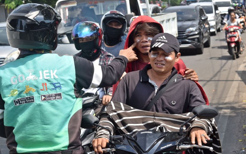 Seorang warga mengoleskan pasta gigi pada warga lainnya yang terdampak sisa gas air mata di Jalan Kemanggisan Raya, Slipi, Jakarta Barat, Kamis (23/5). /Antara Foto