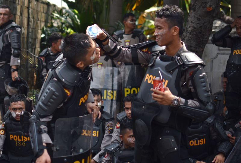 Seorang polisi mengguyur air pada muka rekannya karena terdampak gas air mata saat kerusuhan terjadi di Jalan KS. Tubun, Petamburan, Jakarta Pusat, Rabu (22/5)./ Antara Foto