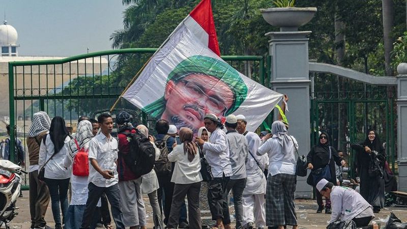  Peserta aksi reuni 212 berfoto dengan latar belakang foto Imam FPI Habib Rizieq usai mengikuti aksi tersebut di kawasan Monas, Jakarta, Senin (2/12/2019). /Foto Antara