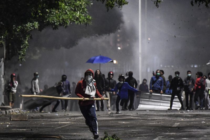 Seorang peserta aksi unjuk rasa berlari sambil membawa sebatang bambu saat unjuk rasa yang berujung kericuhan di kawasan Palmerah, Jakarta, Senin (30/9). /Antara Foto. 