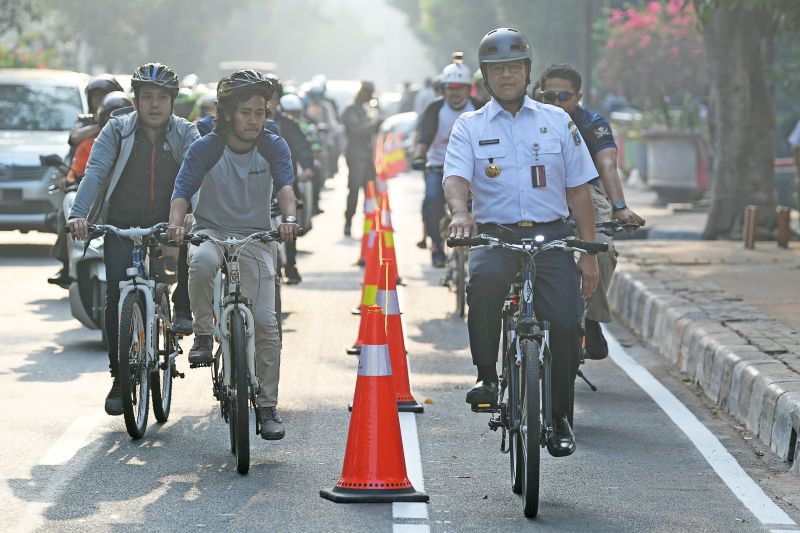 Gubernur DKI Jakarta Anies Baswedan (kanan) berbincang dengan warga ketika bersepeda di Jakarta, Jumat (20/9). /Antara Foto. 