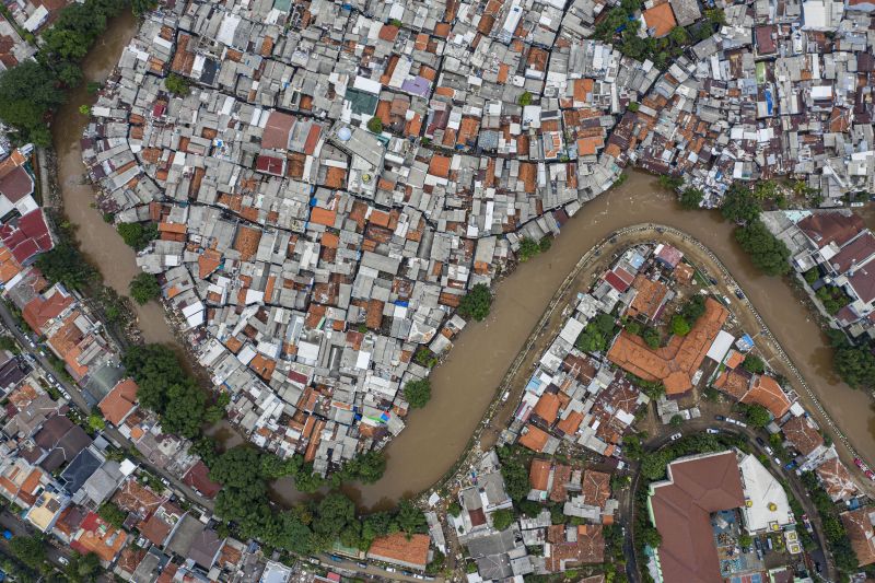 Foto udara suasana wilayah bantaran sungai Ciliwung yang belum dinormalisasi (atas) dan yang sudah dinormalisasi (bawah kanan) di kawasan Bukit Duri, Jakarta, Minggu (5/1/2020). Foto Antara/Muhammad Adimaja.