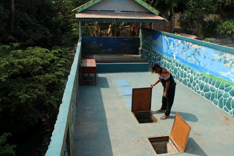 Warga membuka tutup sumur untuk memeriksa Instalasi Pengolahan Air Limbah (IPAL) komunal, di kawasan Kalibaru, Bekasi, Jawa Barat, Selasa (8/10). /Antara Foto.