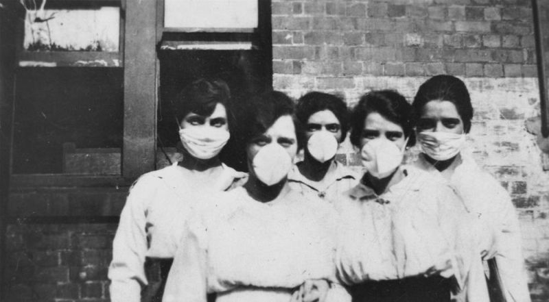 Lima wanita berdiri di depan sebuah bangunan bata, mungkin sebuah rumah sakit, mengenakan masker bedah selama wabah flu Spanyol di Brisbane, 1919. Foto State Library of Queensland/commons.wikimedia.org.