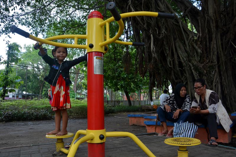 Orang tua membiarkan anaknya menggunakan fasilitas olahraga di Kebonrojo, Kabupaten Jombang, Jawa Timur, Senin (6/1/2019). Foto Antara/Syaiful Arif.