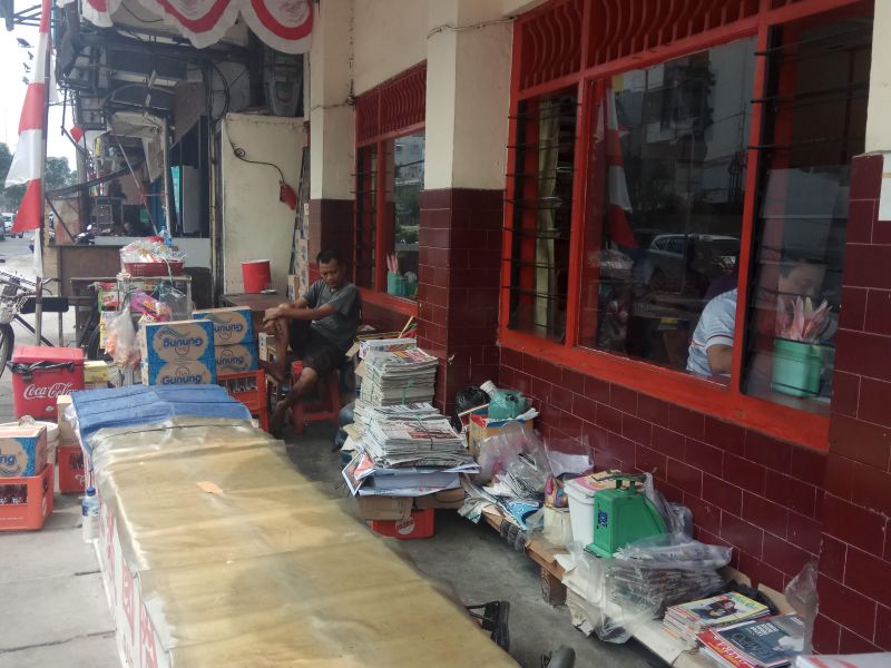 Edi Siswanto (duduk) menunggu koran-koran bekas yang siap dia jual ke tukang loak. Alinea.id/Kudus Purnomo Wahidin.