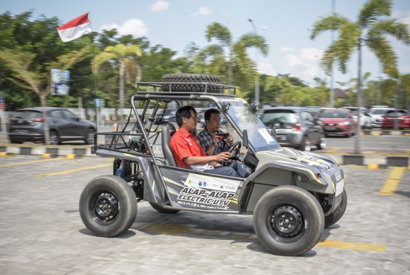 Salah satu mahasiswa ITS perancang mobil listrik Alap-Alap Juniono (kiri) mengendarai mobil listrik tersebut setibanya di Mataram, NTB, Selasa (6/8). /Antara Foto.