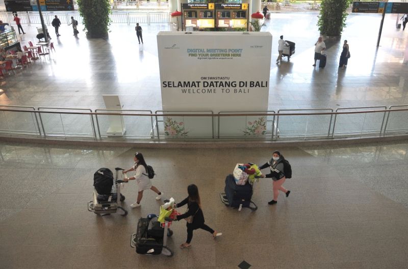 Penumpang pesawat membawa barang bawaannya di Terminal Kedatangan Internasional Bandara Internasional I Gusti Ngurah Rai Bali, Jumat (20/3/2020). Foto Antara/Fikri Yusuf.