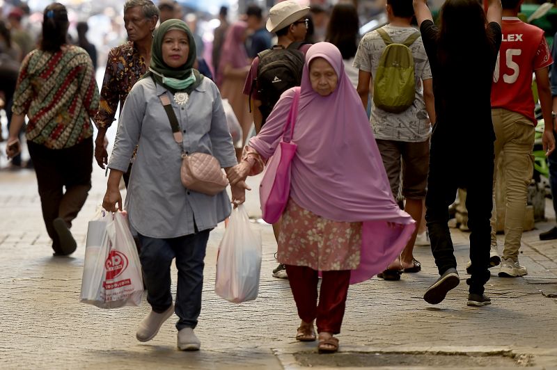 Warga membawa barang bawaan menggunakan tas plastik di Pasar Baru, Jakarta, Jumat (12/7). /Antara Foto.