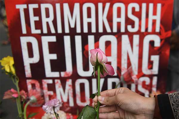 Seorang wanita meletakkan bunga saat aksi dukacita untuk pahlawan demokrasi di Jakarta, Minggu (28/4/2019). /Foto Antara