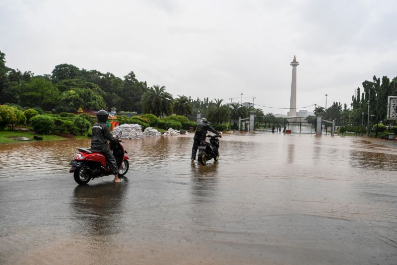 Warga mendorong motor melintasi banjir di kawasan Monas, Jalan Medan Merdeka Barat, Jakarta, Minggu (2/2). Foto Antara/Hafidz Mubarak A