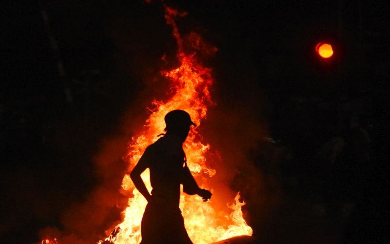 Seorang pengunjuk rasa melintasi benda yang dibakar saat aksi di kawasan Pejompongan, Jakarta, Selasa (24/9). /Antara Foto