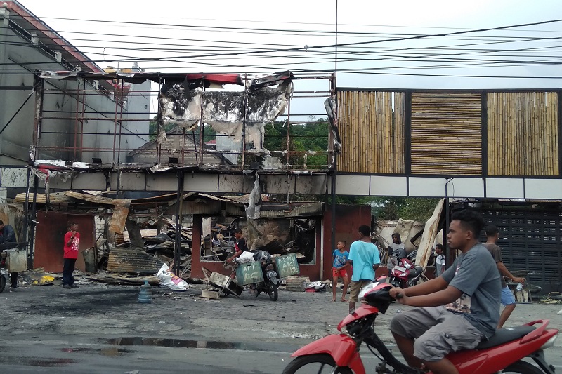 Warga membersihkan puing sisa kerusuhan di salah satu gedung yang terbakar di Manokwari, Papua Barat, Selasa (20/8). / Antara Foto