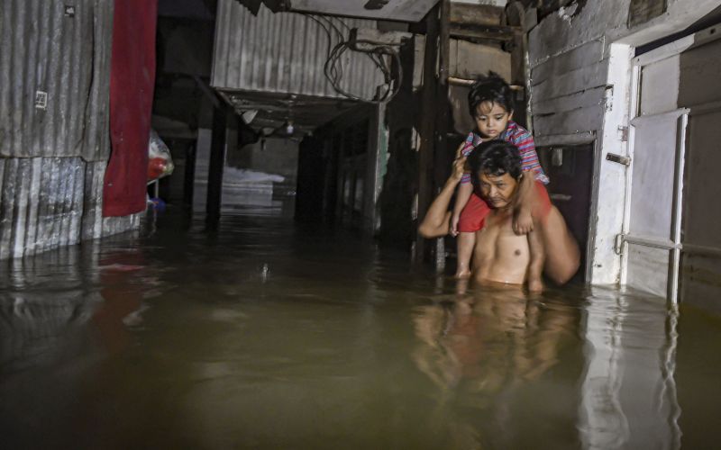 Seorang warga menggendong anaknya melewati banjir di kawasan Kampung Baru, Kembangan, Jakarta Barat, Kamis (2/1). /Antara Foto
