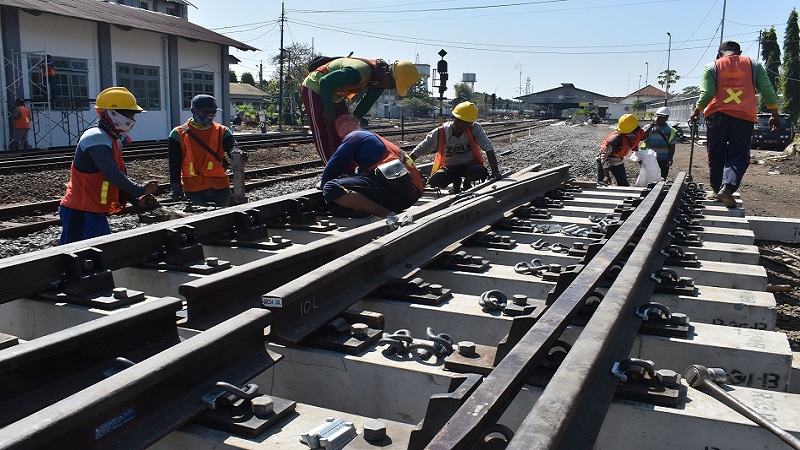Pekerja memasang rel pada bantalan saat pembangunan jalur ganda kereta api (KA) lintas selatan di kawasan Stasiun KA Madiun, Jawa Timur, Rabu (17/7). / Antara Foto