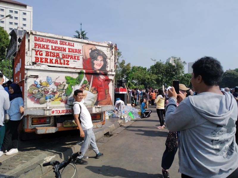 Warga berpose di depan tulisan tutup bak truk dalam acara Pawai Bebas Plastik di kawasan Car Free Day, Jakarta Pusat, Minggu (21/7). Alinea.id/Robertus Rony Setiawan