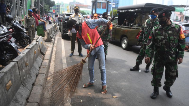 Pelanggar PSBB dijatuhi sanksi sosial dengan menyapu jalanan di Tanah Abang, Jakarta, Rabu (13/5/2020). Foto Antara/Akbar Nugroho Gumay