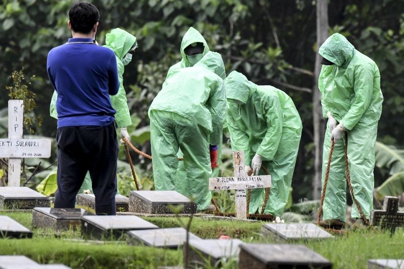 Petugas pemakaman menurunkan peti jenazah pasien COVID-19 di TPU Pondok Ranggon, Jakarta, Senin (30/3/2020).Foto Antara/Muhammad Adimaja.
