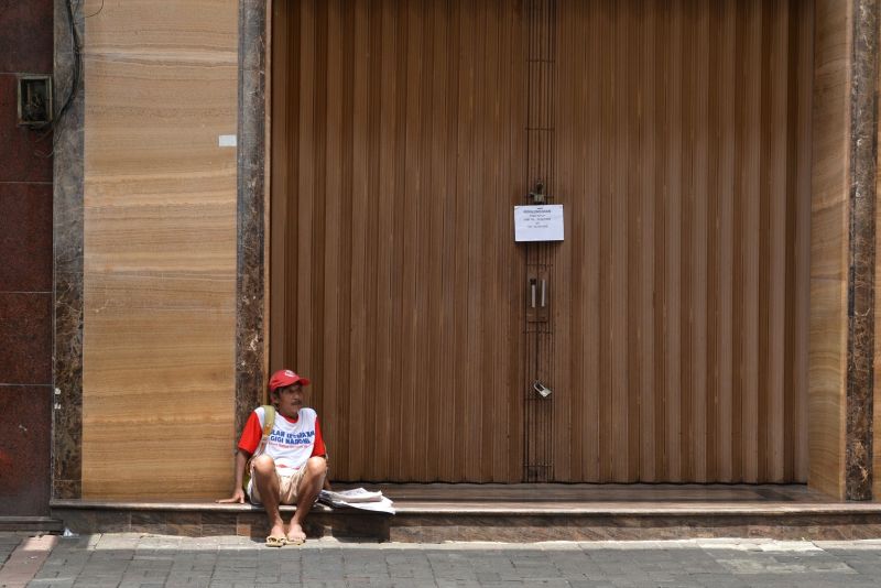 Seorang penjual koran beristirahat di depan toko yang tidak beroperasi di kawasan perdagangan Pasar Baru, Jakarta, Selasa (24/3/2020). Foto Antara/Aditya Pradana Putra.