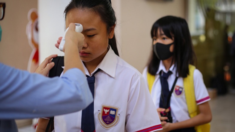 Petugas mengukur suhu tubuh murid saat memasuki sekolah di tengah pandemi coronavirus baru (Covid-19). Foto Antara/Fauzan.
