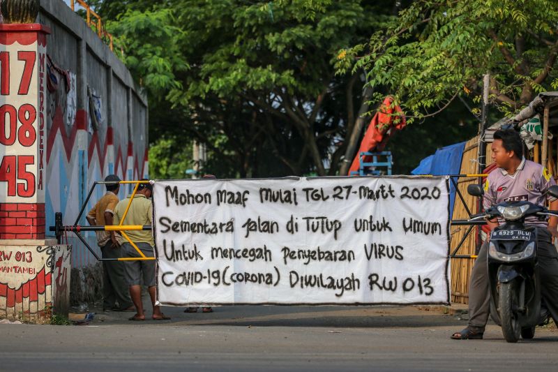 Warga beraktivitas di depan akses masuk kampung yang ditutup di Kalideres, Jakarta, Sabtu (28/3/2020). Foto Antara/Fauzan.
