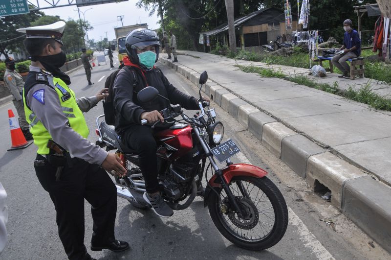 Polisi memberhentikan pengendara motor yang melintas di perbatasan Bekasi dengan Karawang daerah Kedungwaringin, Kabupaten Bekasi, Jawa Barat, Sabtu (25/4/2020). Foto Antara/ Fakhri Hermansyah.