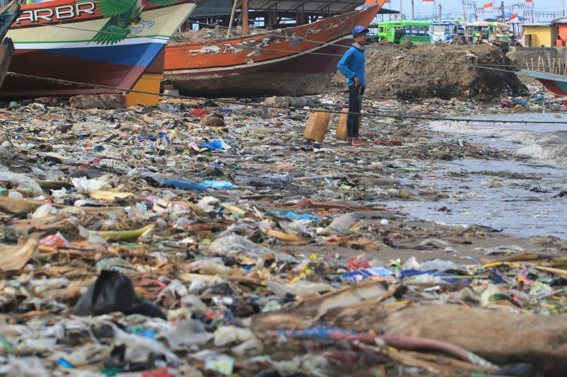 Nelayan menyandarkan perahunya di bibir pantai yang dipenuhi sampah plastik di Desa Dadap, Indramayu, Jawa Barat, Senin (26/11/2018). Foto Antara.