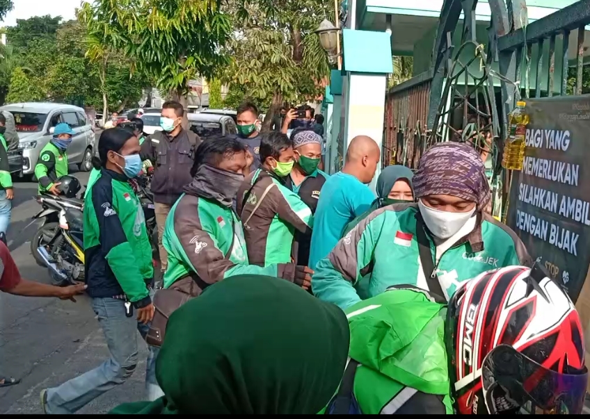Masyarakat berkerumun saat mengambil bansos dari PKB yang digantung di pagar Graha Gus Dur, Kota Surabaya, Jatim, Jumat (15/5/2020). Alinea.id/Adi Suprayitno