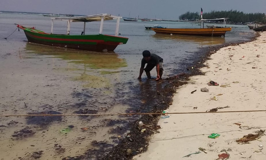 Mustaghfirin, 48 tahun, membersihkan pek di bibir pantai Pulau Pari, Agustus 2020. Foto dokumentasi Forum Peduli Pulau Pari (FP3).