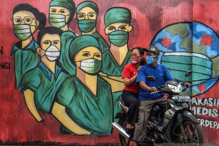  Pengendara motor melintas di depan mural tentang pandemi virus corona atau COVID-19 di Jalan Raya Jakarta-Bogor, Depok, Jawa Barat, Jumar (3/4/2020). Mural tersebut ditujukan sebagai bentuk dukungan kepada tenaga medis yang menjadi garda terdepan dalam menghadapi COVID-19 di Indonesia. /Foto Antara
