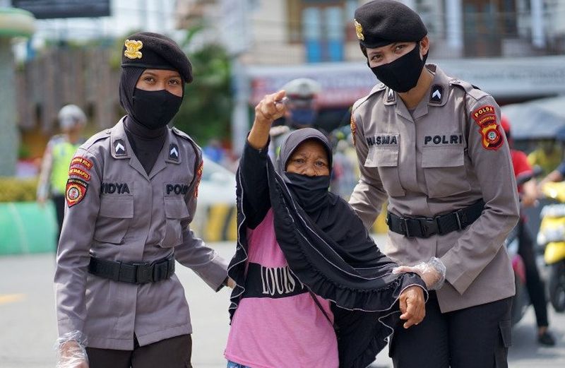 Sejumlah polisi wanita (polwan) menuntun seorang nenek menyeberang jalan saat pembagian masker gratis di Kota Gorontalo, Gorontalo, Rabu (22/4/2020). /Foto Antara