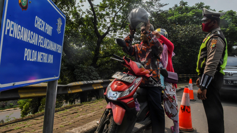 Polisi mengimbau pengguna kendaraan bermotor yang akan masuk ke Ibu Kota saat PSBB di perbatasan Depok-DKI Jakarta, Senin (13/4/2020). Foto Antara/Muhammad Adimaja