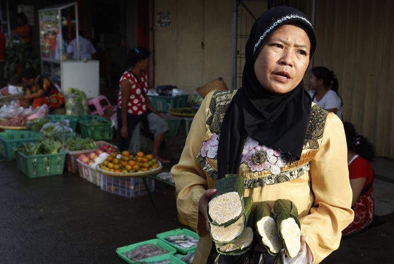 Seorang pedagang menawarkan tempe kepada pelanggannya di sebuah pasar. Foto Reuters/Enny Nuraheni.