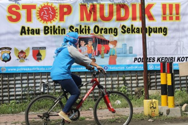 Warga melintas di depan spanduk bertuliskan 'stop mudik' di Kota Kediri, Jawa Timur, Rabu (8/4). /Foto Antara