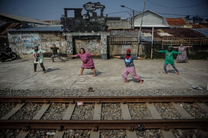 Warga berjemur sekaligus berolahraga di samping rel kereta api di Andir, Bandung, Jawa Barat, Rabu (15/4). /Foto Antara