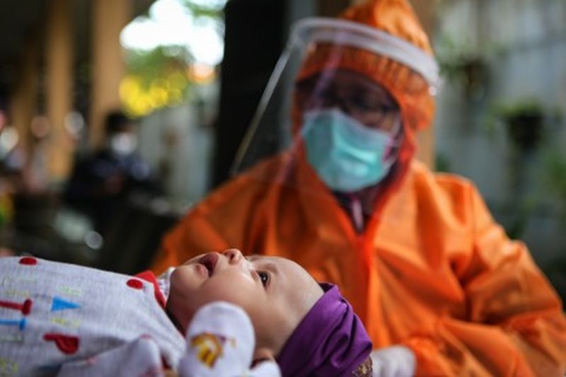 Petugas menggunakan alat pelindung diri (APD) menimbang berat badan bayi saat imunisasi di Puskesmas Karawaci Baru, Kota Tangerang, Banten, Rabu (13/5). /Foto Antara