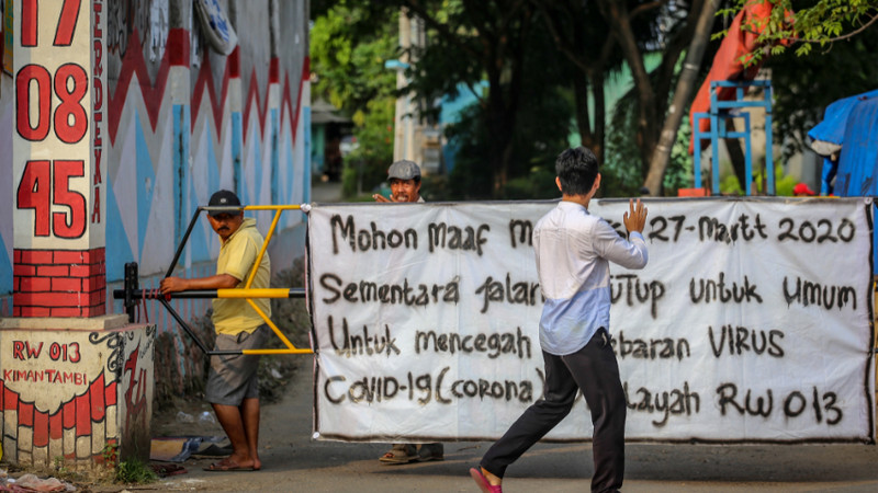 Warga berakativitas di depan akses masuk kampung yang ditutup di Kalideres, Jakarta, Sabtu (28/3/2020). Foto Antara/Fauzan