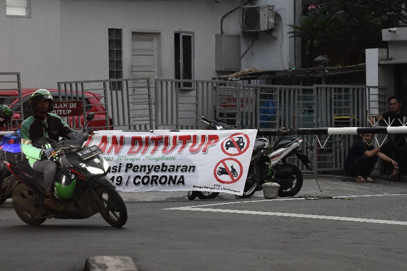 Pengemudi ojek online melintasi spanduk penutupan jalan di kawasan Pondok Pinang, Jakarta, Rabu (1/4). Foto Antara/Puspa Perwitasari.