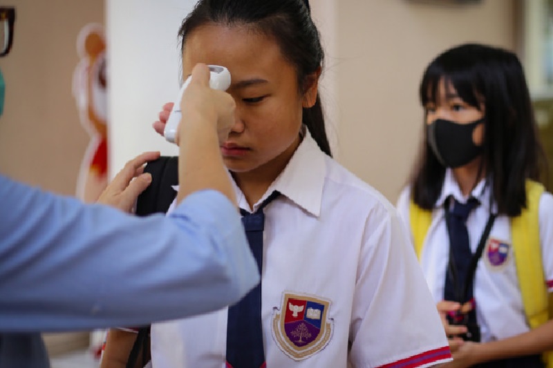 Petugas mengukur suhu tubuh para siswa saat hendak memasuki sekolah di tengah pandemi Covid-19. Foto Antara/Fauzan