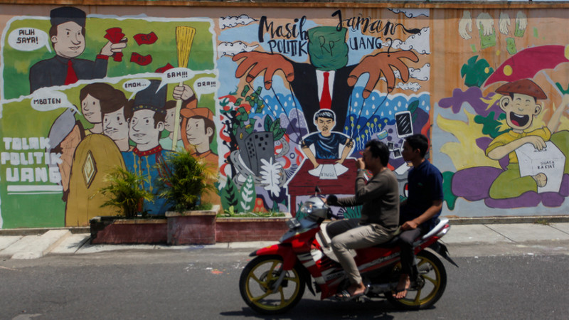 Warga melintasi mural bertema Pilkada 2020 di Kelurahan Sondakan, Kecamatan Laweyan, Kota Surakarta, Jateng, Selasa (10/12/2019). Foto Antara/Maulana Surya