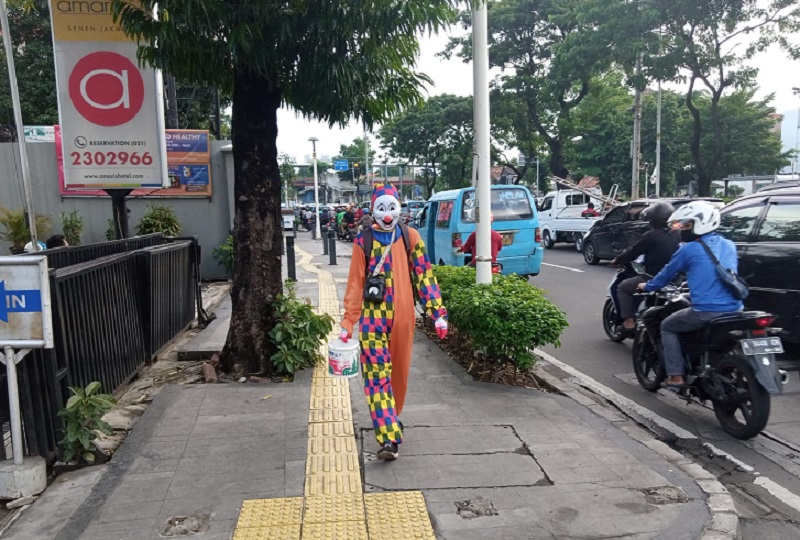 Seorang badut keliling melintasi trotoar Jalan Salemba Raya, Jakarta Pusat, Kamis (23/12). Alinea.id/Kudus Purnomo Wahidin