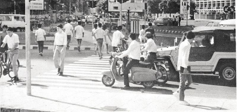  Seorang pesepeda (paling kiri) tengah menyeberang jalan yang mulai padat sepeda motor dan mobil./Repro buku Djakarta Membangun (1972).