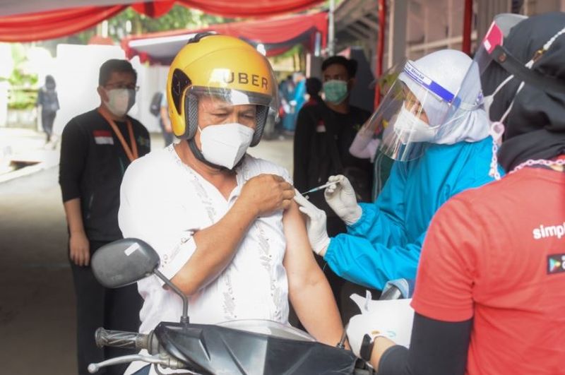  Petugas vaksinator menyuntikan vaksin Covid-19 kepada seorang pengendara sepeda motor secara layanan tanpa turun atau drive thru./Foto Dokumentasi Humas Setkab/Setkab.go.id).