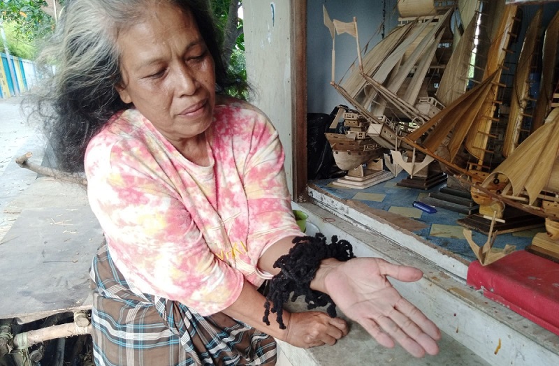 Komariah, 60 tahun, menunjukkan butiran debu yang kerap menempel di atap dan perabotan rumahnya di kawasan Marunda, Cilincing, Jakarta Utara, Sabtu (21/1). Alinea.id/Kudus Purnomo Wahidin