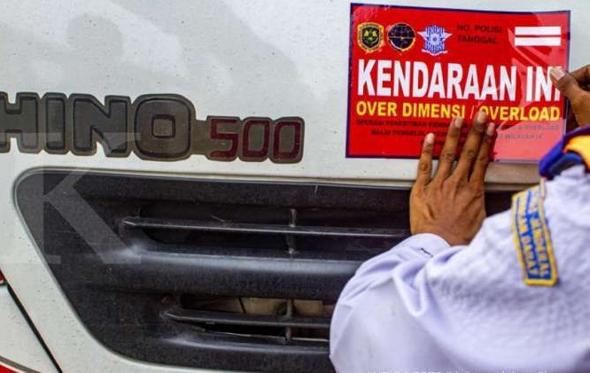 Petugas menempelkan stiker pada truk saat operasi penertiban 'over dimension' dan 'over load' di KM 41 tol Jakarta -Cikapek, Karawang, Jawa Barat, Jumat (13/3/2020). /Foto Antara
